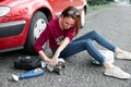 A young girl sits near a broken car and makes repairs to the electric generator, next to her there are bad parts, tools and first Royalty Free Stock Photo