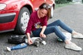 A young girl sits near a broken car and makes repairs to the electric generator, next to her there are bad parts, tools and first Royalty Free Stock Photo