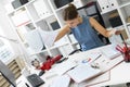 A young girl sits in the office at the computer desk and dismantles the mountain of documentation.