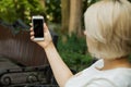 A young girl sits outdoors on a bench in a park and holds a phone Royalty Free Stock Photo