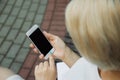 A young girl sits outdoors on a bench in a park and holds a phone Royalty Free Stock Photo