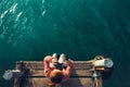 Young Girl Sits On The Pier And Looks At Sea Through Binoculars, Top View. Adventure Vacation Discovery Travel Concept Royalty Free Stock Photo