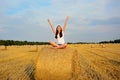A young girl sits on a stack of straw with her hands up. Freedom, romance Royalty Free Stock Photo