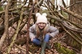 Young girl sits under shelter of tree branches, full length