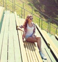 Young girl sitting on bench in city park on sunny summer Royalty Free Stock Photo