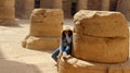 Young girl sitting bored on the ruins of an old column in the temple of Kalabsha