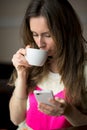 Young girl, sitting cafe with cup of coffee and read messages phone looking pictures on the tablet. Royalty Free Stock Photo