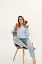 Young girl sitting on a chair holding a fresh red rose in her hand. Royalty Free Stock Photo