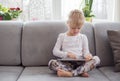 Young girl sitting on couch and using tablet computer Royalty Free Stock Photo