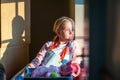 Young girl sitting in the early morning light from a window with her shadow cast behind her
