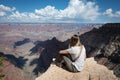 young girl sitting on the edge of the cliff of the Grand Canyon