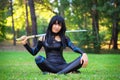 Young girl sitting on the grass and holding samurai sword. Royalty Free Stock Photo