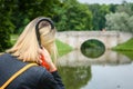 Young girl sitting on the grass in the Park by the lake with a red umbrella-close-up view from the back. Royalty Free Stock Photo