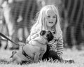 A little girl sitting with her dog in the park at a dog show