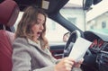 Shocked woman in car reading insurance paper