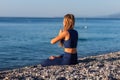 Young girl sitting in Lotus pose on the beach at sunset Royalty Free Stock Photo