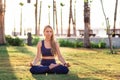 Young girl sitting in Lotus pose practicing Yoga in the park near seafront line at sunset sunrise Royalty Free Stock Photo