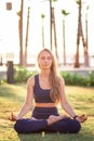 Young girl sitting in Lotus pose practicing Yoga in the park near seafront line at sunset sunrise Royalty Free Stock Photo