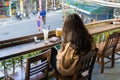 Young girl sitting in the open cafe with Hanoi street on background in Hanoi city, Vietnam