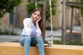 Young girl sitting outside with headache, migraine. Women`s problems, stress