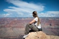 girl sitting on the rock of the cliff looking at the impressive landscape of the grand canyon