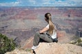 girl sitting on the rock of the cliff looking at the impressive landscape of the grand canyon