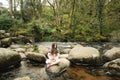 Young girl sitting on a rock in a river, looking thoughtful. Royalty Free Stock Photo