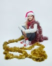 Young girl is sitting in a Santa hat. photo session in the studio on a white background Royalty Free Stock Photo