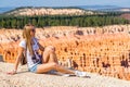 Young girl sitting by the scenic view of stunning red sandstone hoodoos