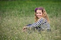 Young girl sitting in spring flowers on the meadow and smiling Royalty Free Stock Photo