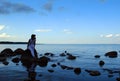 A young girl is sitting at sunset on rocks that lie in the water, near the shore of the Gulf of Finland. Royalty Free Stock Photo