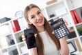 A young girl sitting at a table and holding a phone and a calculator. Royalty Free Stock Photo