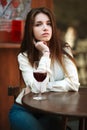 Young girl sitting at table in summer cafe with glass of wine Royalty Free Stock Photo