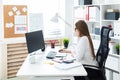 Young girl sitting at the table and working with a computer, documents and calculator Royalty Free Stock Photo