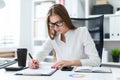 Young girl sitting at the table and working with a computer, documents and calculator Royalty Free Stock Photo