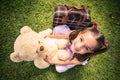 Young girl sitting with a teddy bear and suitcase