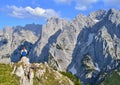 Young girl is sitting on the top of the mountains, enjoying beautiful view on the mountain range Kaisergebirge, Austria.