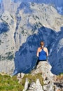 Young girl is sitting on the top of the mountains, enjoying beautiful view on the mountain range Kaisergebirge, Austria. Royalty Free Stock Photo