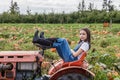 Young girl sitting on tractor in a green farm field