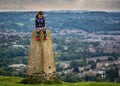 Young girl sitting on triangulation point on Little Solsbury Hill, overlooking the World Heritage City of Bath, Somerset, UK Royalty Free Stock Photo