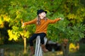 Young girl sitting up the wooden stump and smiling. Autumn background. Copy space Royalty Free Stock Photo