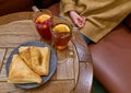 Girl sitting in front of a wooden table with a two cups of tea and layered cakes