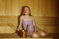 Young girl is sitting in a wood sauna. Bucket. Steam room and relaxation Royalty Free Stock Photo