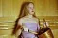 Young girl is sitting in a wood sauna. Bucket. Steam room and relaxation Royalty Free Stock Photo