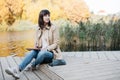 A young girl sketching near a lake in the autumn forest.