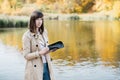 A young girl sketching near a lake in the autumn forest.