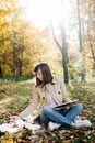 A young girl sketching near a lake in the autumn forest. Sketching. The girl is in a great mood and happy