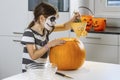 Young girl with skull face paint carving a pumpkin Royalty Free Stock Photo