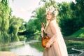 young girl with a small guitar near a waterfall.