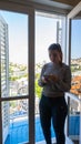 Young girl with smart phone in a room with balcony. Red head woman with grey long shirt. White wood Blinds and door